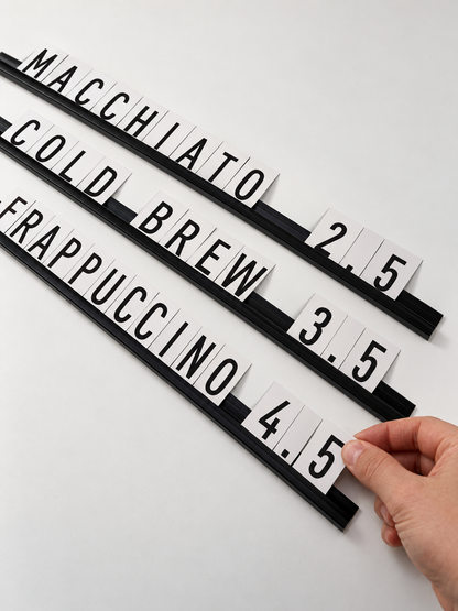 A hand changes a price card on black interchangeable letter board rails