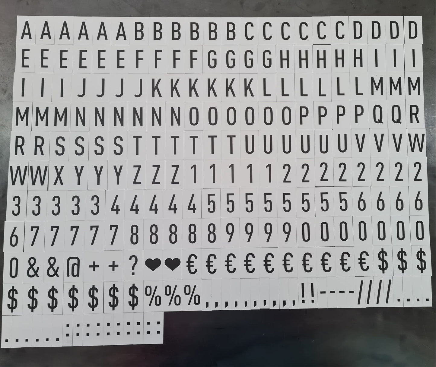 Sheet of typewriter-style letter and number stickers on a dark surface