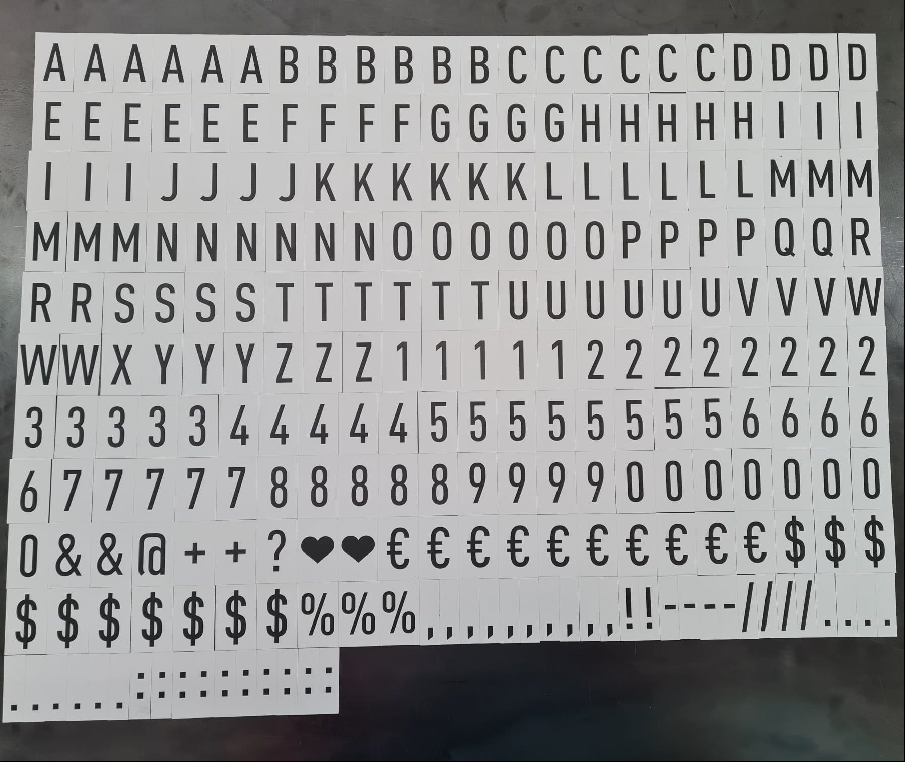 Sheet of typewriter-style letter and number stickers on a dark surface