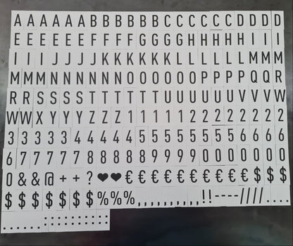 Sheet of typewriter-style letter and number stickers on a dark surface