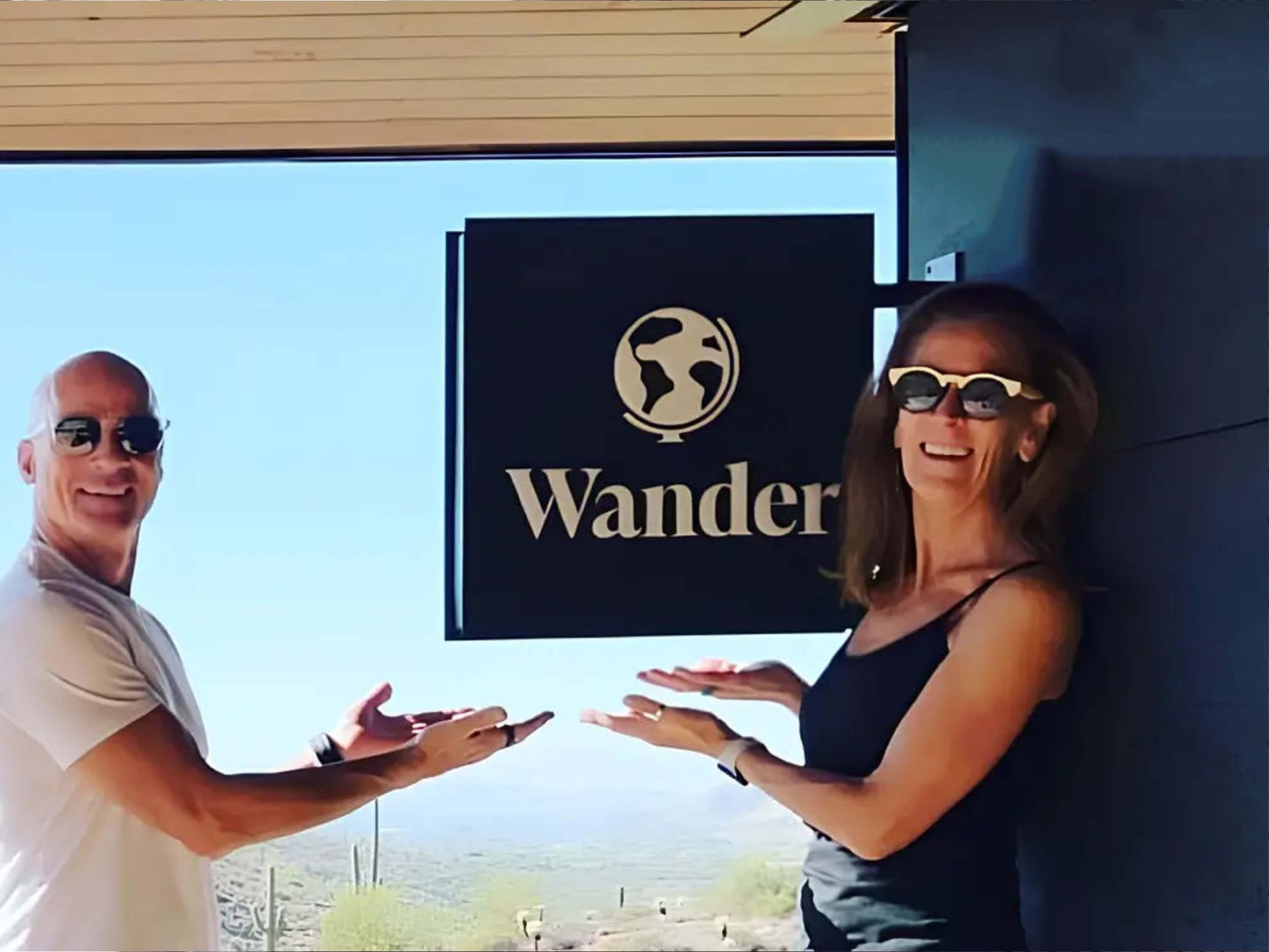 Two people standing in front of a building with a 'Wander' sign.