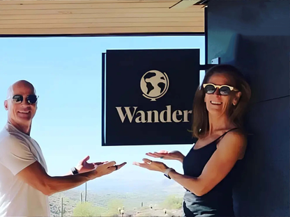 Two people standing in front of a building with a 'Wander' sign.
