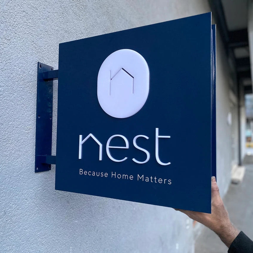 Nest sign on a wall with a person's hand holding it