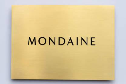 Gold plaque with 'MONDAINE' branding on a light gray background
