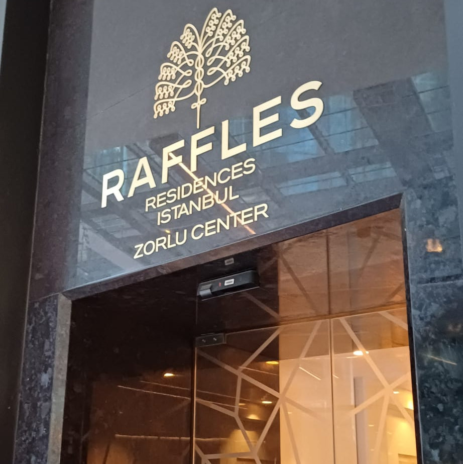 Entrance to Raffles Residences with a tree logo on a dark background