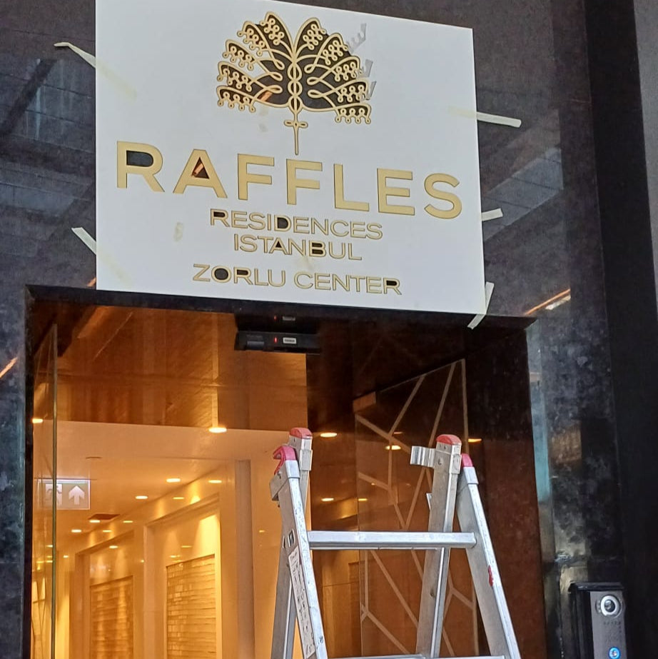 Ladder in front of a building entrance with Raffles Residences & Suites sign above.