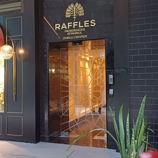 Raffles hotel entrance with decorative plants in red pots.