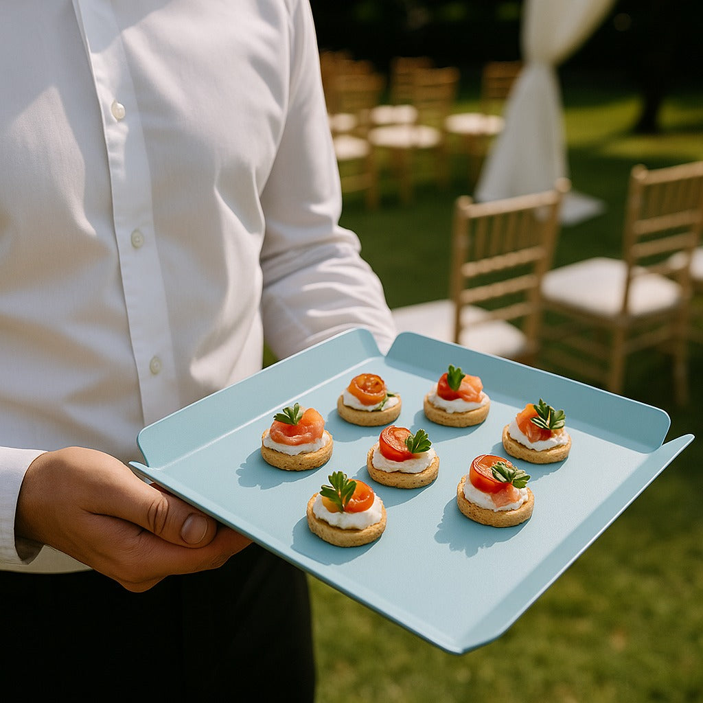 Person holding a tray of small appetizers outdoors