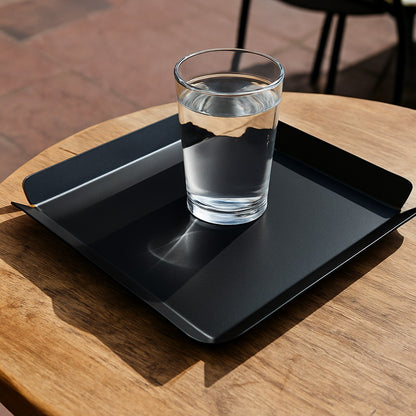 Glass of water on a black tray with a wooden table background