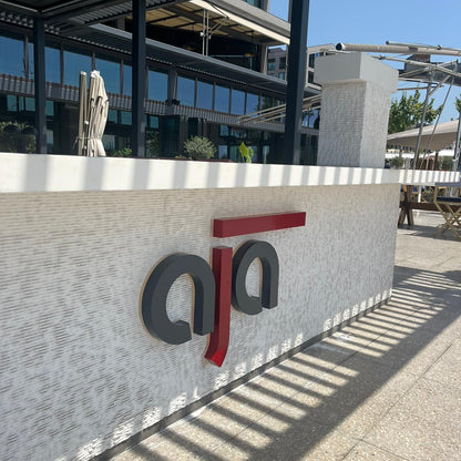 Logo of a company on a wall with a building in the background