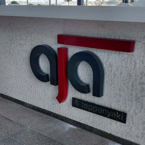 Logo of a company on a wall with a person partially visible in the foreground.
