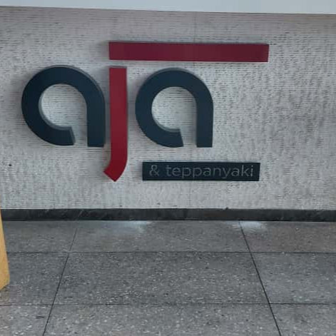 Two red stools in front of a wall with 'aja' logo and text.