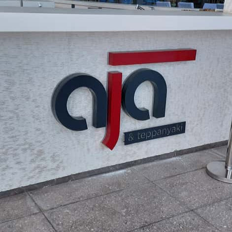 Logo of AIA on a building facade with glass windows in the background