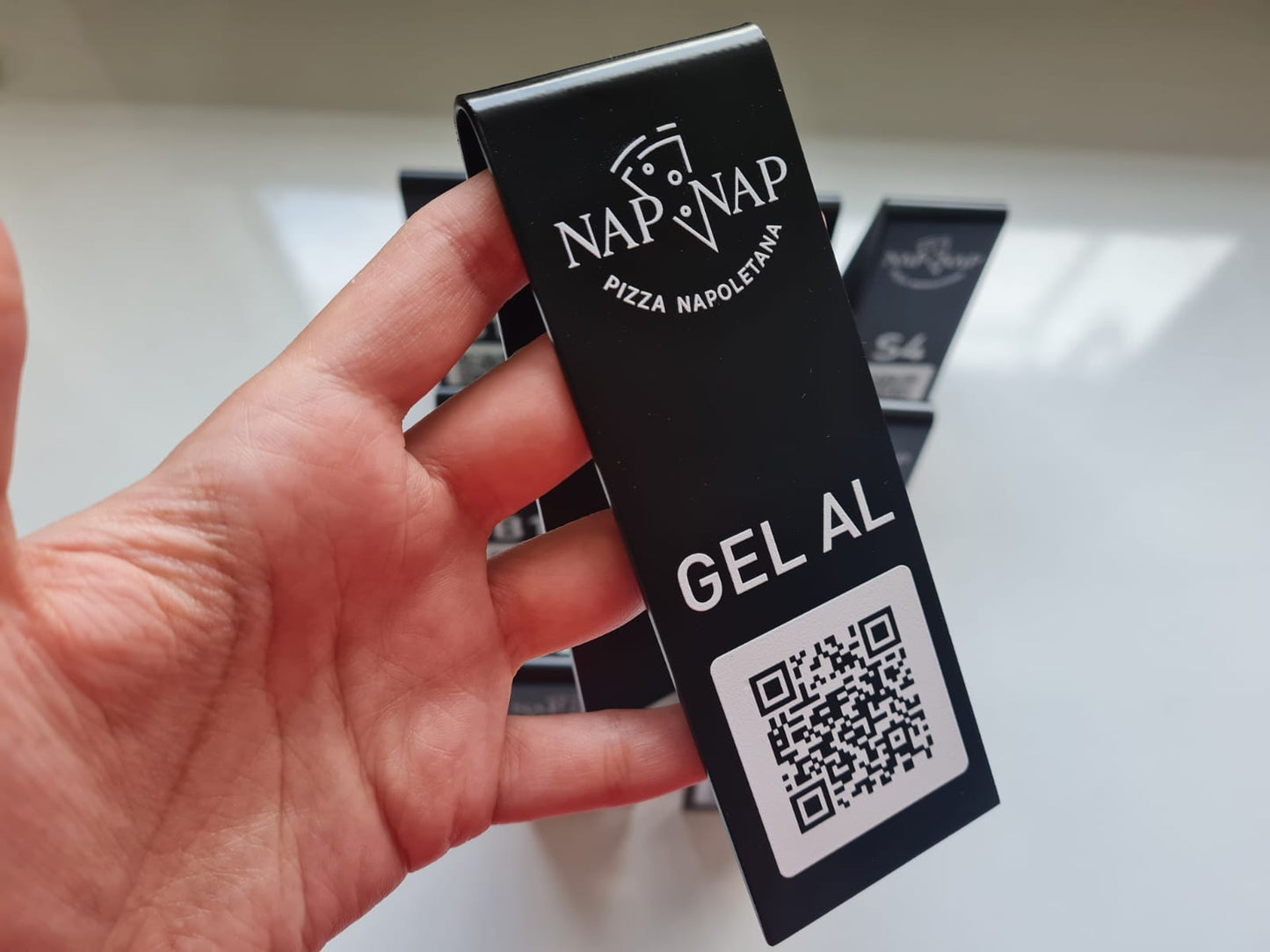 Hand holding a black package labeled 'Nap-Vap' with a QR code on a white background