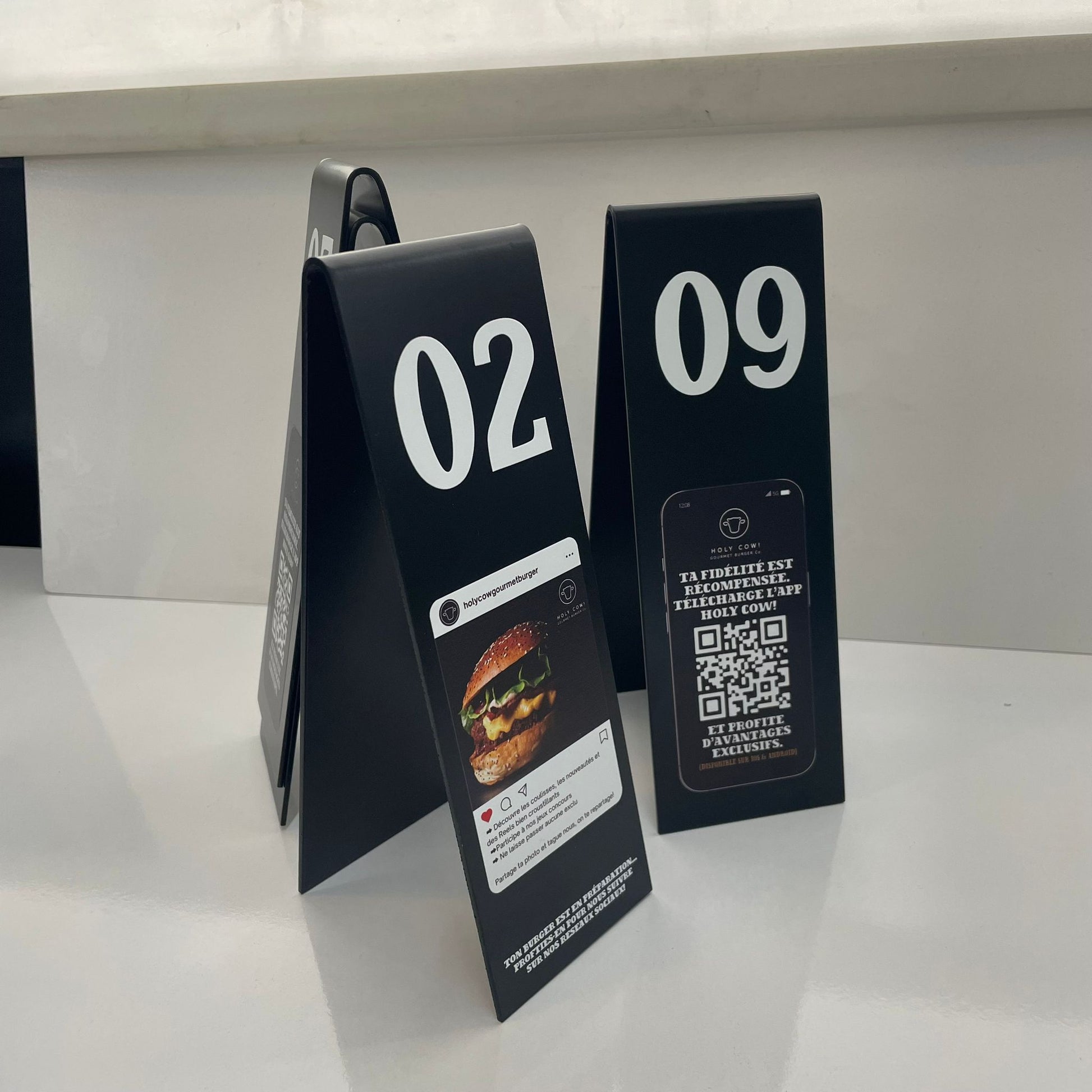 Two black table tents with digital menu items on a white surface