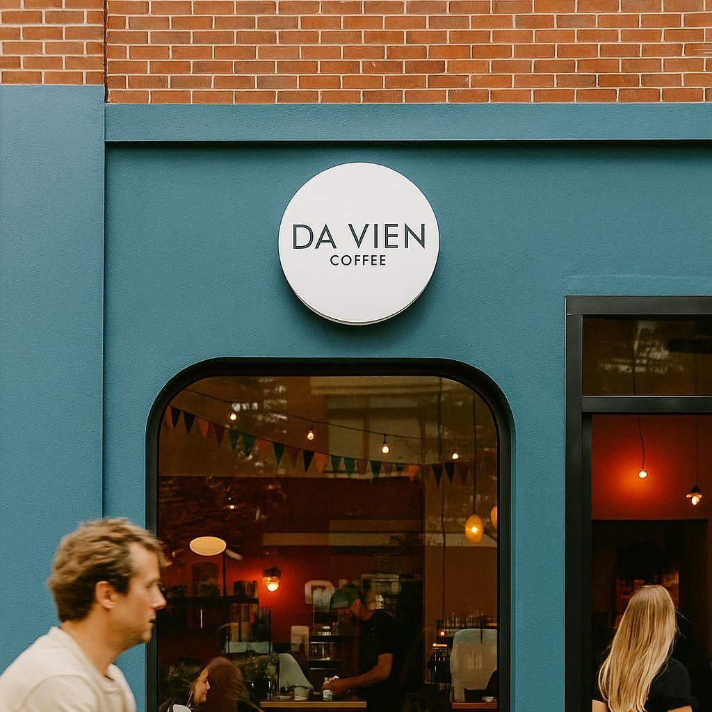People walking past a coffee shop named 'DA Vien Coffee' with a teal exterior.