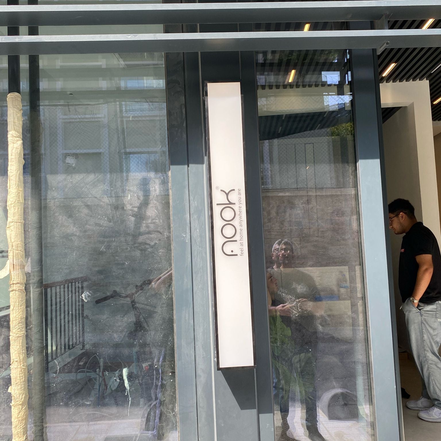 Glass door with 'nook' logo reflecting people and a building.