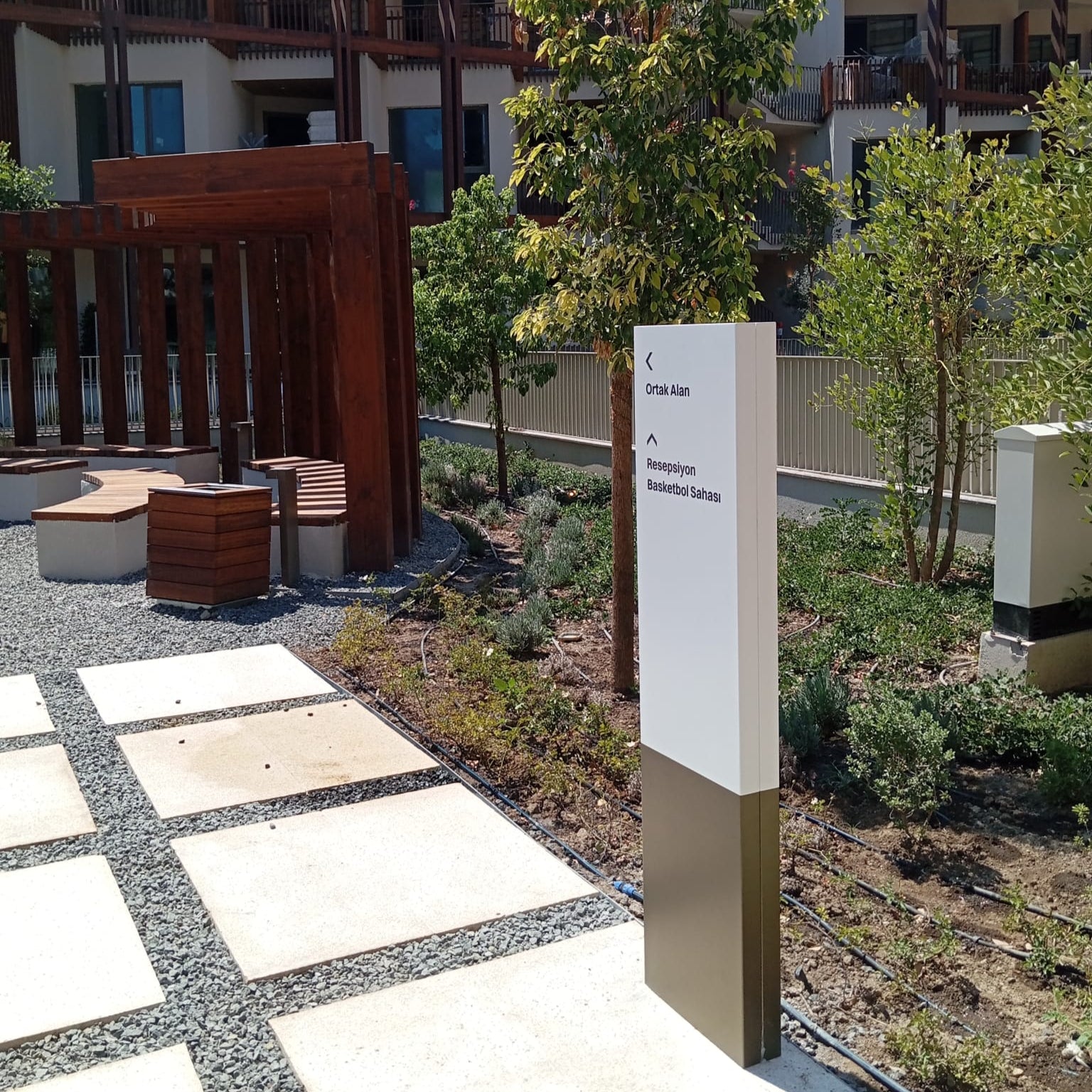 Paved area with a signpost and trees in front of a building