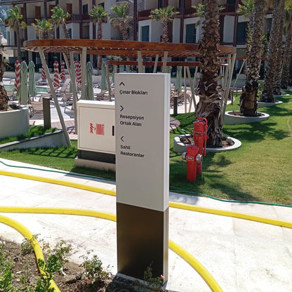 Outdoor setting with a signpost, palm trees, and a building in the background.