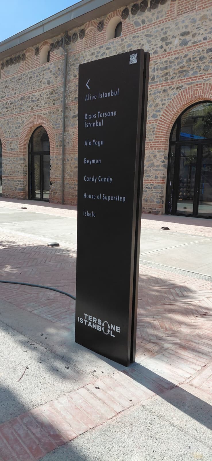 Black directional sign in front of a building with architectural details