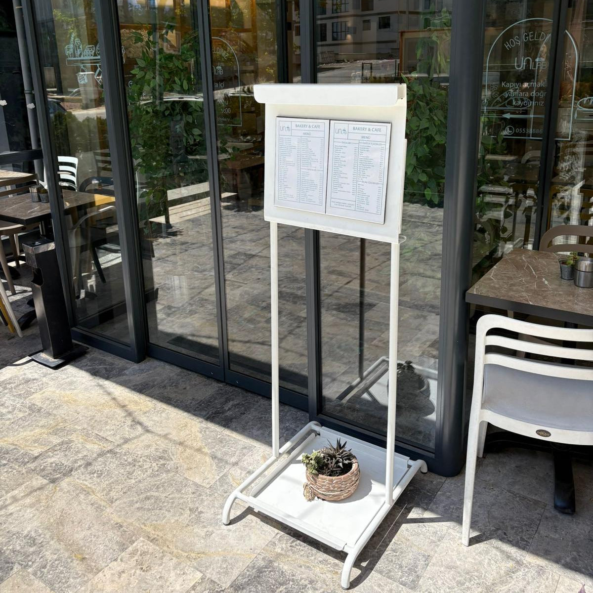Outdoor seating area with a menu board in front of a glass door with 'unlab' branding.