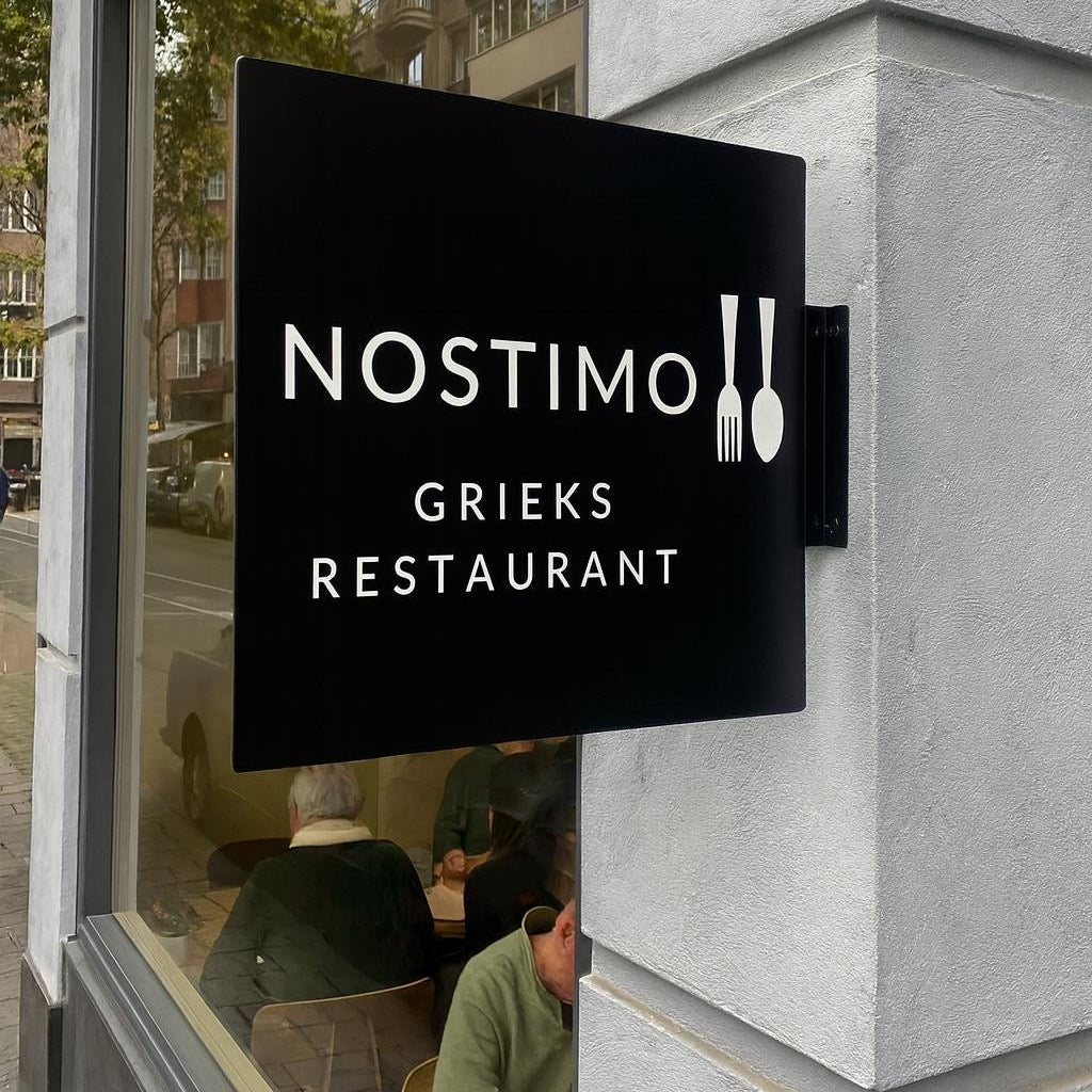 Nostimo Grieks Restaurant sign on a building exterior with reflection of street scene.