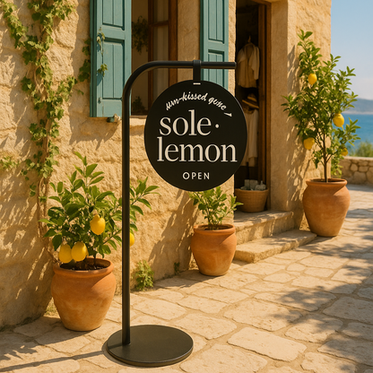 Sole Lemon sign in front of a stone building with green shutters and potted plants.