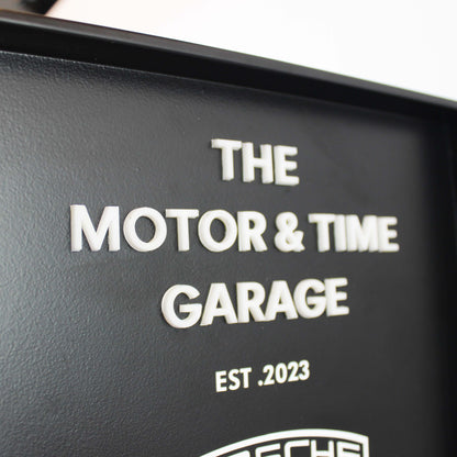 Black sign with 'The Motor & Time Garage' and Porsche logo