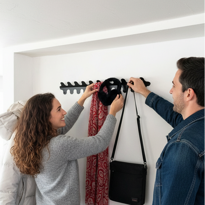 Two people hanging a black bag on a wall-mounted rack in a room.