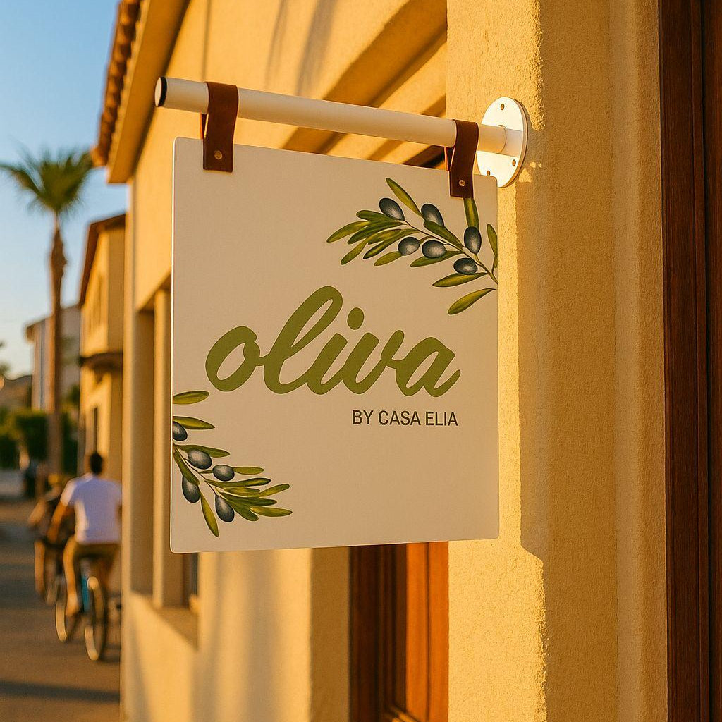 Sign with 'oliva by Casa Elia' on a building exterior with people walking in the background.