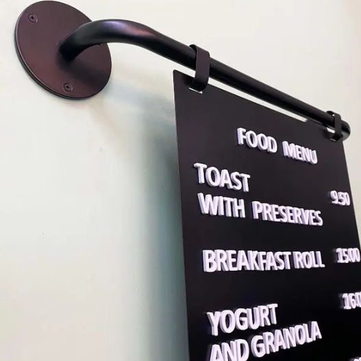 Black sign with white text displaying a food menu on a wall.