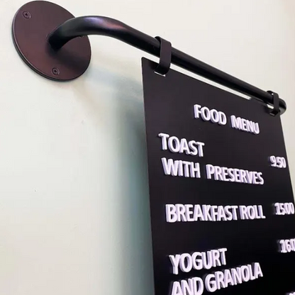 Black sign with white text displaying a food menu on a wall.