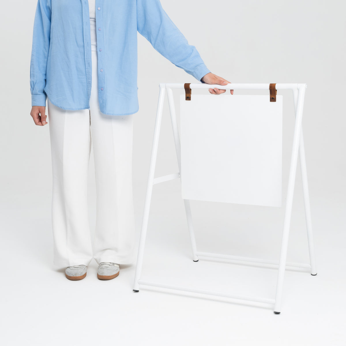Person carrying an unprinted white A-frame sign for scale