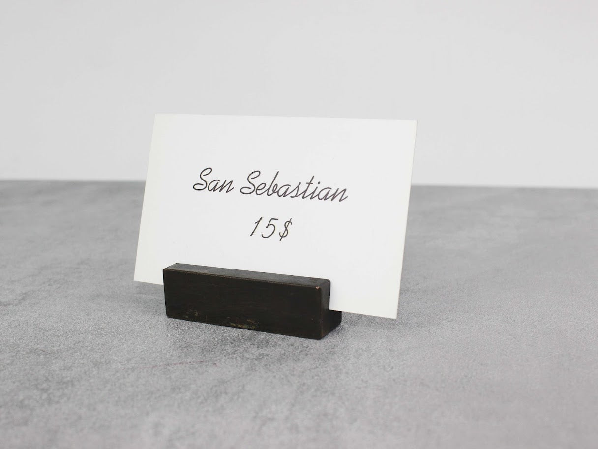 Aged metal card holder on a countertop displaying business cards, adding a vintage touch to the setting.